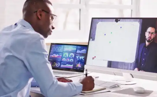 Professional reviewing dashboards across two monitors